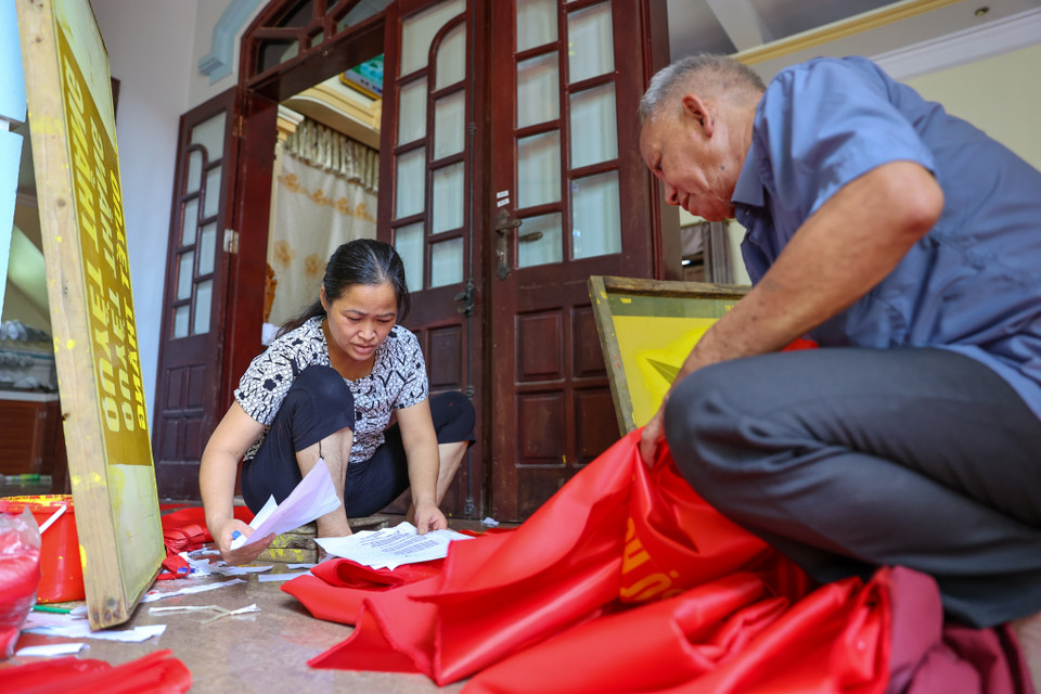 Bên cạnh việc áp dụng công nghệ sản xuất hiện đại để năng suất cao hơn, song ở Từ Vân, một số hộ vẫn giữ gìn cách làm cờ truyền thống như gia đình chị Vương Thị Nhung 3 đời truyền nhau thêu cờ Tổ quốc. (Ảnh: Minh Sơn/Vietnam+)