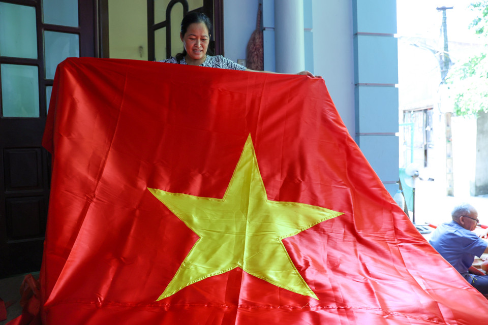 Chị Nhung cũng cho biết làm cờ may đơn giản hơn so với cờ thêu. Một ngày chị có thể làm ra hàng trăm chiếc cờ may, nhưng chiếc cờ thêu thì phải mất hàng tuần. (Ảnh: Minh Sơn/Vietnam+)