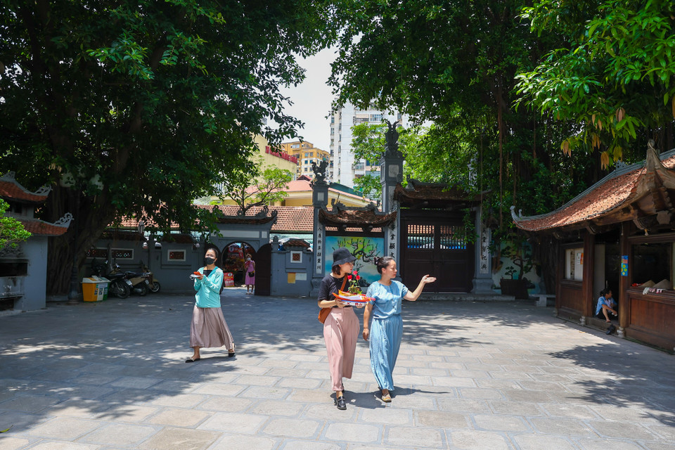 Các bạn trẻ khi mua mâm lễ sẽ được người bán hướng dẫn đầy đủ từ cách đặt lễ cũng như đọc văn khấn bên trong chùa. (Ảnh: Minh Sơn/Vietnam+)