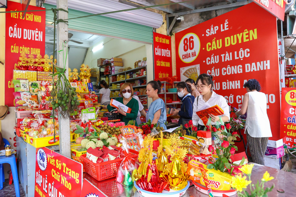 Ngay từ sớm, cửa hàng của chị Quỳnh (đường Chùa Hà, Hà Nội) đã tấp nập khách hàng đến nhờ sắp đồ lễ cũng như viết sớ cầu duyên. (Ảnh: Minh Sơn/Vietnam+)