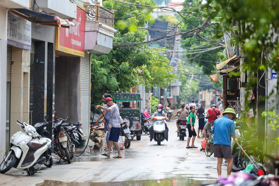 Khắp các con ngõ ở Tứ Liên, các hộ dân cùng nhau dọn dẹp bùn đất, rác thải trôi dạt, làm sạch các đồ đạc bị ngập nước và sắp xếp lại nhà cửa. (Ảnh: Minh Sơn/Vietnam+)