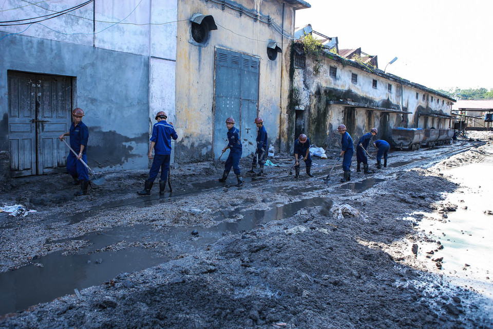Hàng chục công nhân thay phiên nhau đào xới, dọn dẹp những nơi lũ bùn càn quét. (Ảnh: Minh Sơn/Vietnam+)