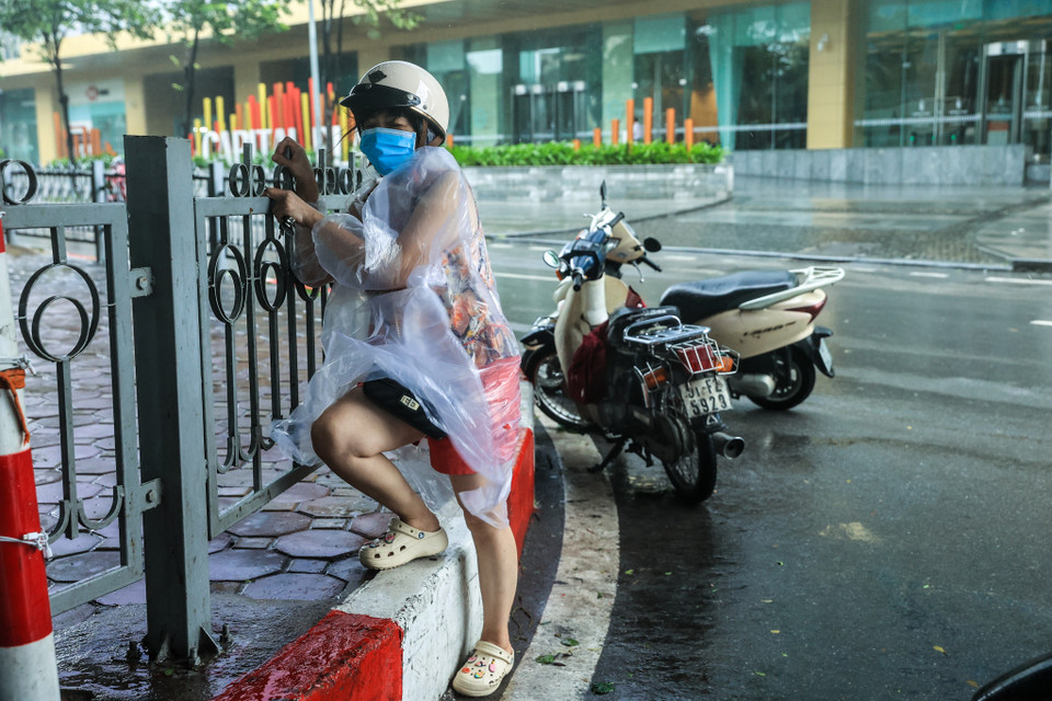 Một người dân phải bíu chặt vào hàng rào trước cơn gió mạnh thổi từ trong các tòa nhà ra. (Ảnh: Minh Sơn/Vietnam+)