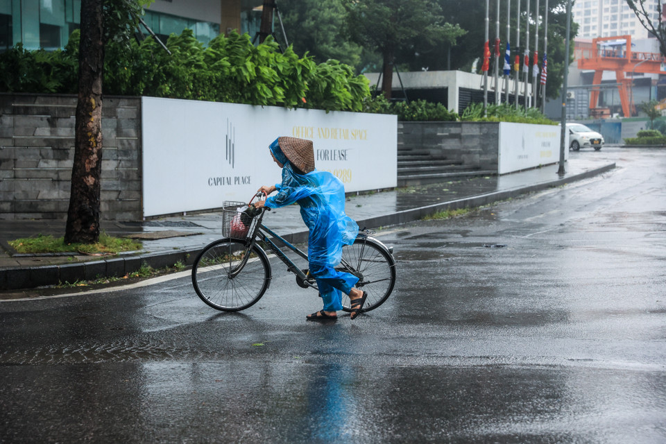 Hàng loạt phương tiện di chuyển qua đây đều khó khăn, nhiều người ngã rạp vì gió bão quá mạnh. (Ảnh: Minh Sơn/Vietnam+)