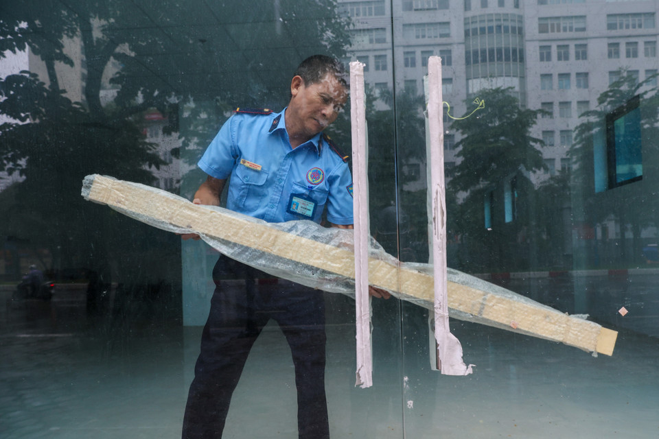 Bảo vệ tại một toà nhà trên đường Hoàng Quốc Việt dùng thanh gỗ chắn cửa kính đề phòng gió giật mạnh, giúp bảo vệ tài sản. (Ảnh: Minh Sơn/Vietnam+)