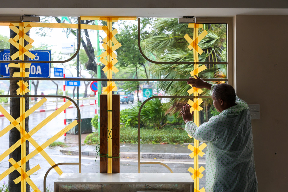 Người bảo vệ tại cửa hàng cho biết, ông cùng đồng nghiệp đã ứng trực tại đây từ hôm qua đến giờ và đã dán hết cửa kính đề phòng gió giật mạnh. (Ảnh: Minh Sơn/Vietnam+)