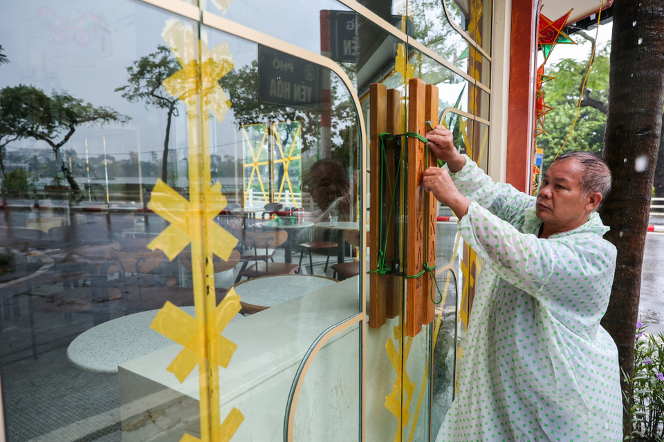 "Cách làm này giúp tăng cường độ bền của kính, hạn chế khả năng vỡ vụn khi có gió to," người đàn ông này chia sẻ. (Ảnh: Minh Sơn/Vietnam+)
