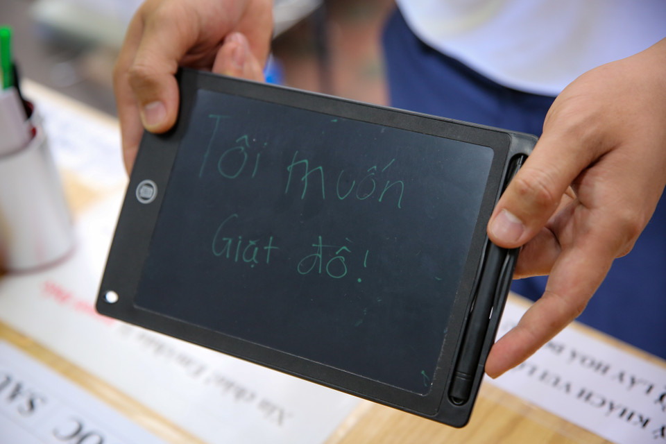 Cửa hàng cũng có đầy đủ các công cụ hỗ trợ như bảng hướng dẫn, bảng viết để khách hàng có thể giao tiếp được với nhân viên. (Ảnh: Minh Sơn/Vietnam+)