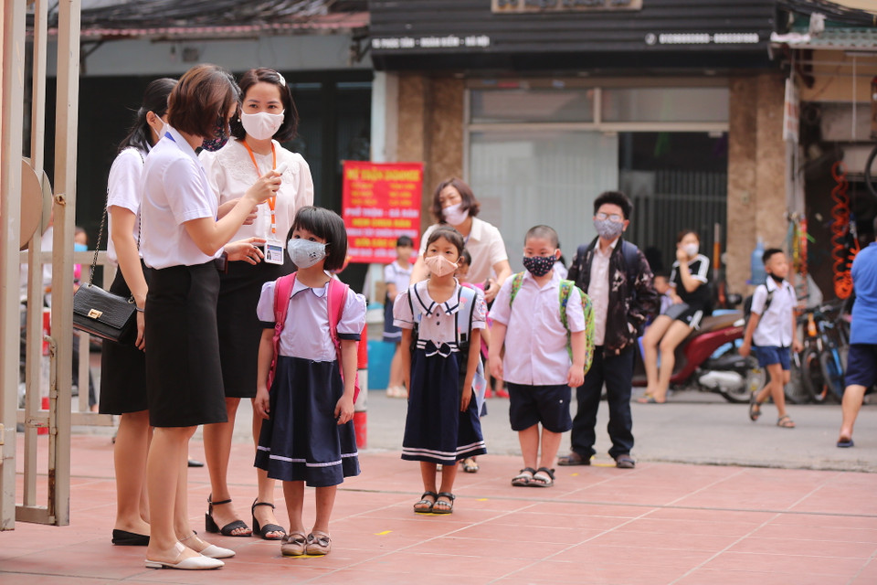 Các học sinh trước khi vào trường sẽ được lần lượt xếp hàng đo thân nhiệt, sát khuẩn tay. (Ảnh: Minh Sơn/Vietnam+)