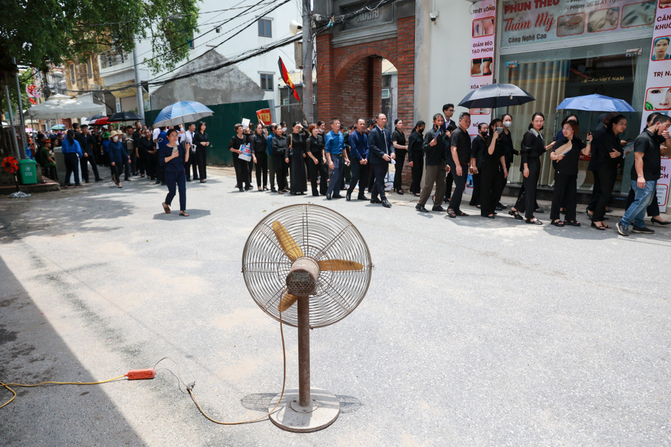 Người dân Lại Đà không ai bảo ai cùng nhau mang quạt trong nhà ra bật để làm dịu cơn nóng mùa hè cho đồng bào đến viếng Tổng Bí thư. (Ảnh: Minh Sơn/Vietnam+)