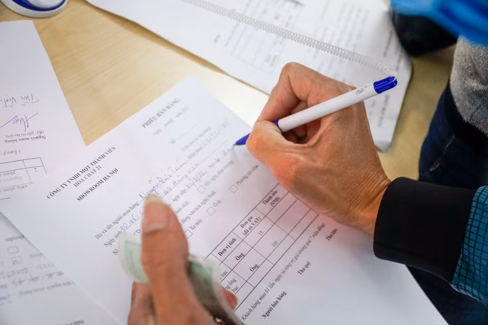 Người dân khi mua pháo phải xuất trình chứng minh nhân dân, điền thông tin của người mua, các sản phẩm chọn mua để cửa hàng lưu trữ thông tin. (Ảnh: PV/Vietnam+)