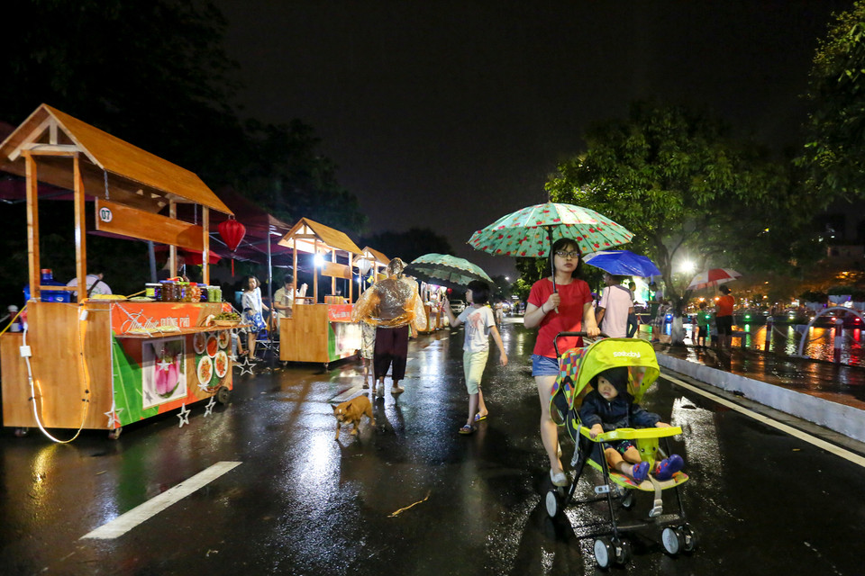 Cơn mưa tầm tã không ngăn được hàng trăm người dân đến thưởng lãm tuyến phố mới của Hà Nội. (Ảnh: Minh Sơn/Vietnam+)