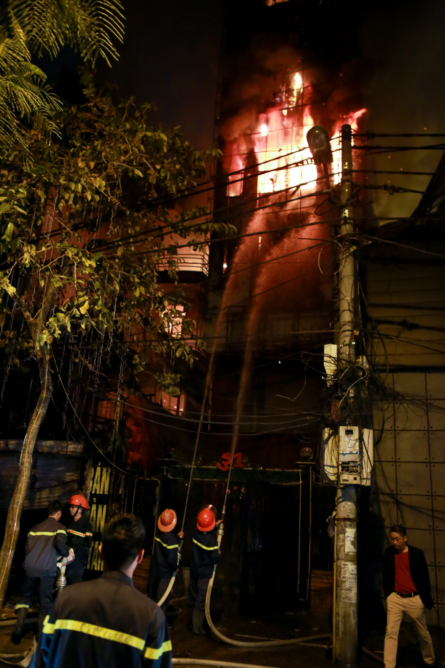 Lực lượng chức năng dùng vòi rồng bao vây đám cháy. (Ảnh: Minh Sơn/Vietnam+)