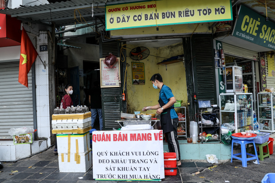 Hàng quán ăn bán trong nhà vẫn được hoạt động bình thường. Tuy nhiên những cửa hàng này phải thực hiện giãn cách tối thiểu 2m giữa người với người hoặc giữ khoảng cách tối thiểu 1m và có tấm chắn giữa các vị trí ngồi. (Ảnh: Minh Sơn/Vietnam+)