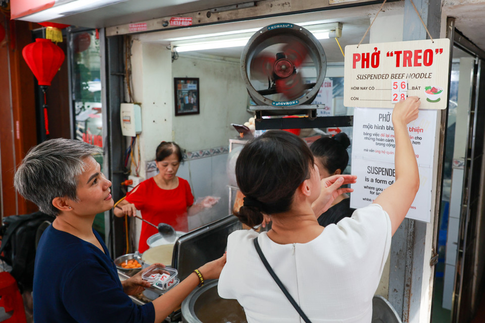 Ngoài chữ "phở "treo," chủ quán còn làm biển ghi dòng chữ "Đây là một hình thức từ thiện bằng việc để lại một phần ăn cho những hoàn cảnh khó khăn hơn trong cộng đồng mà vẫn ủng hộ quán ăn địa phương" bằng cả tiếng Anh lẫn tiếng Việt. (Ảnh: Minh Sơn/Vietnam+)