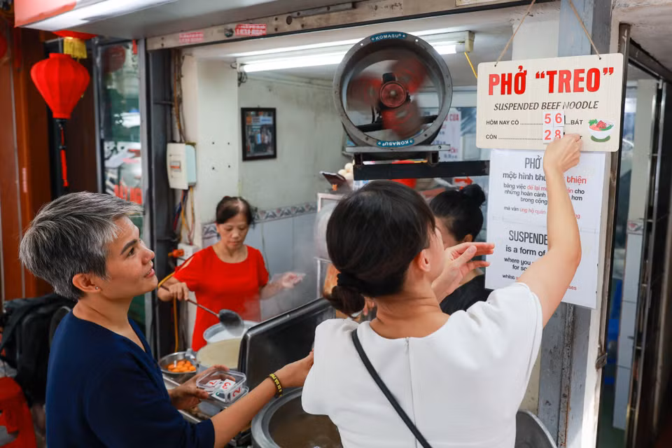 Ngoài chữ "phở "treo," chủ quán còn làm biển ghi dòng chữ "Đây là một hình thức từ thiện bằng việc để lại một phần ăn cho những hoàn cảnh khó khăn hơn trong cộng đồng mà vẫn ủng hộ quán ăn địa phương" bằng cả tiếng Anh lẫn tiếng Việt. (Ảnh: Minh Sơn/Vietnam+)