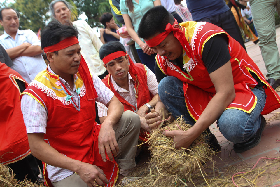 Mỗi đội thi sẽ bện những sợi rơm lại với nhau để làm thành chiếc đế cho cối giã gạo. (Ảnh: Minh Sơn/Vietnam+)