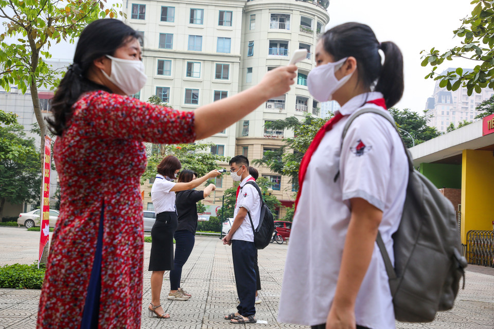 Các em học sinh được giữ khoảng cách an toàn theo khuyến cáo của bộ Y tế để kiểm tra thân nhiệt. (Ảnh: Minh Sơn/Vietnam+)