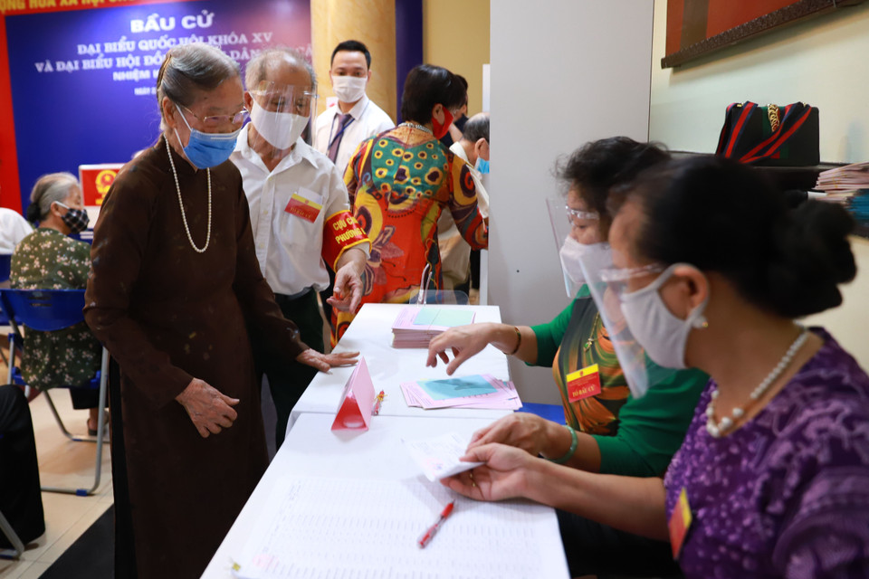Tổ bầu cử tiến hành phát phiếu bầu cử cho cụ Thuận. Cụ Thuận cũng là một trong những người đầu tiên bỏ phiếu tại phường Điện Biên. (Ảnh: Hoài Nam/Vietnam+)