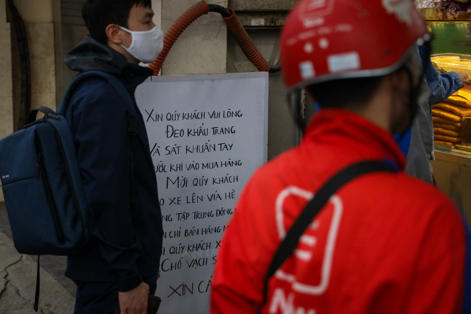Cửa hàng này cũng treo biển khuyến cáo khách hàng đeo khẩu trang và sát khuẩn tay trước khi mua hàng. (Ảnh: Minh Sơn/Vietnam+)