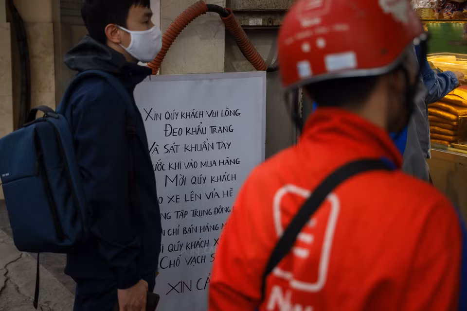 Cửa hàng này cũng treo biển khuyến cáo khách hàng đeo khẩu trang và sát khuẩn tay trước khi mua hàng. (Ảnh: Minh Sơn/Vietnam+)