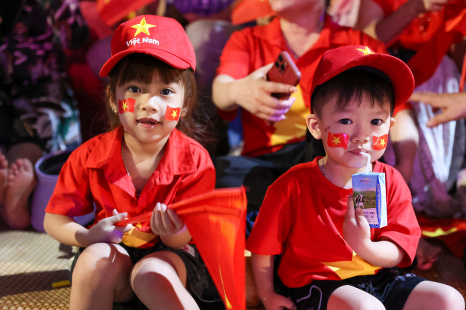Những em bé được phụ huynh chuẩn bị áo cờ đỏ sao vàng đưa ra khu vực diễn ra lễ diễu binh từ sớm. (Ảnh: Minh Sơn/Vietnam+)