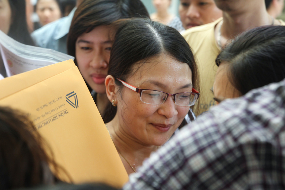 Mướt mải mồ hôi để mua được một bộ hồ sơ cho con, em mình. (Ảnh: Minh Sơn/Vietnam+)