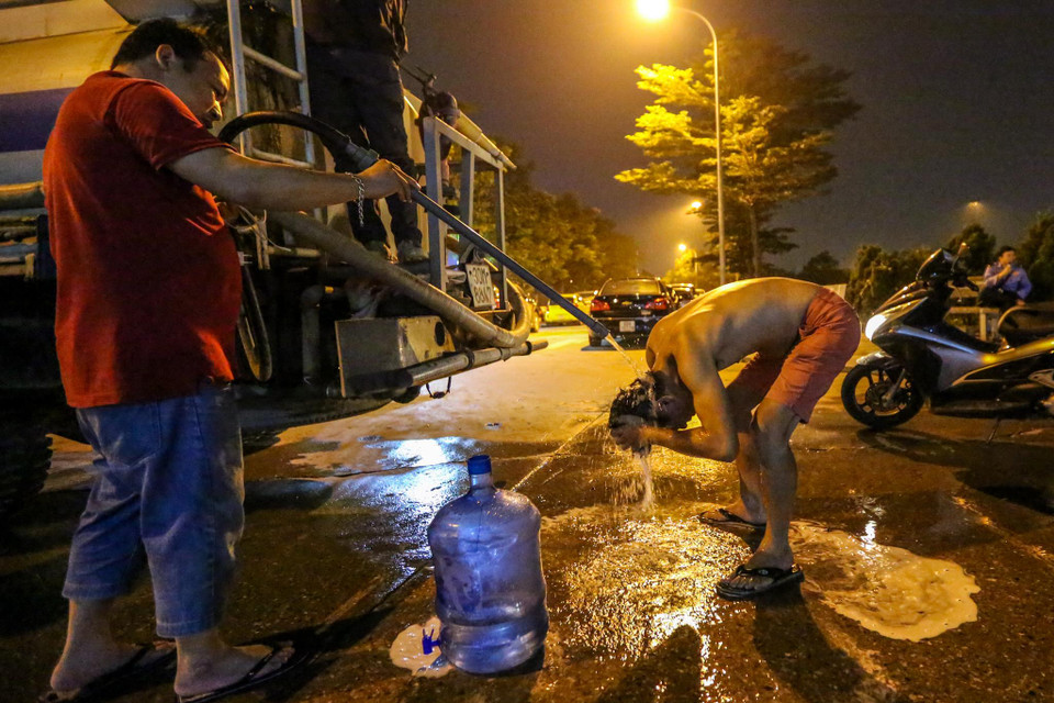 Đến khoảng 1h30 sáng, khi chiếc xe téc chuẩn bị rời đi, một số người tranh thủ lấy chút nước còn lại để tắm gội. (Ảnh: Minh Sơn/Vietnam+)