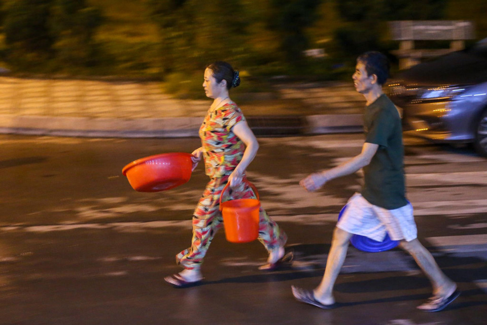 Nhiều người tỏ ra vội vã đến lấy nước vì chỉ có 1 xe téc mà lại phục vụ cho nhu cầu rất lớn của cư dân. (Ảnh: Minh Sơn/Vietnam+)