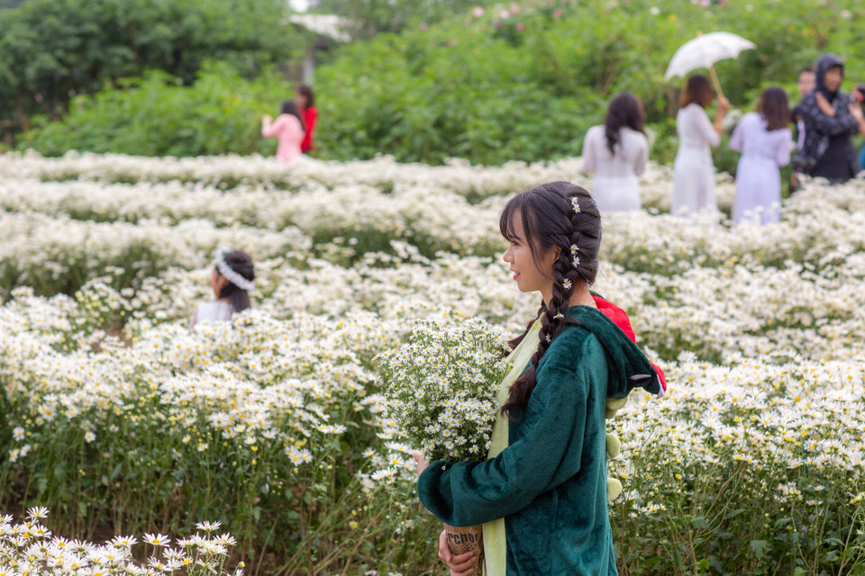 Nhiều bạn gái chọn cho mình những góc chụp ưng ý nhất để tạo dáng và khoe sắc cùng hoa. (Ảnh: Minh Sơn/Vietnam+)