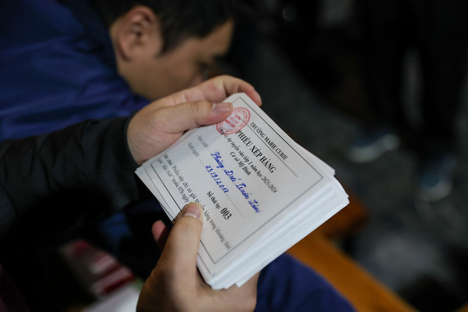 Các phụ huynh sẽ lần lượt vào bàn đăng ký ghi tên, tuổi con em mình vào tờ danh sách và chờ tới lượt đăng ký nộp hồ sơ. (Ảnh: Minh Sơn/Vietnam+)