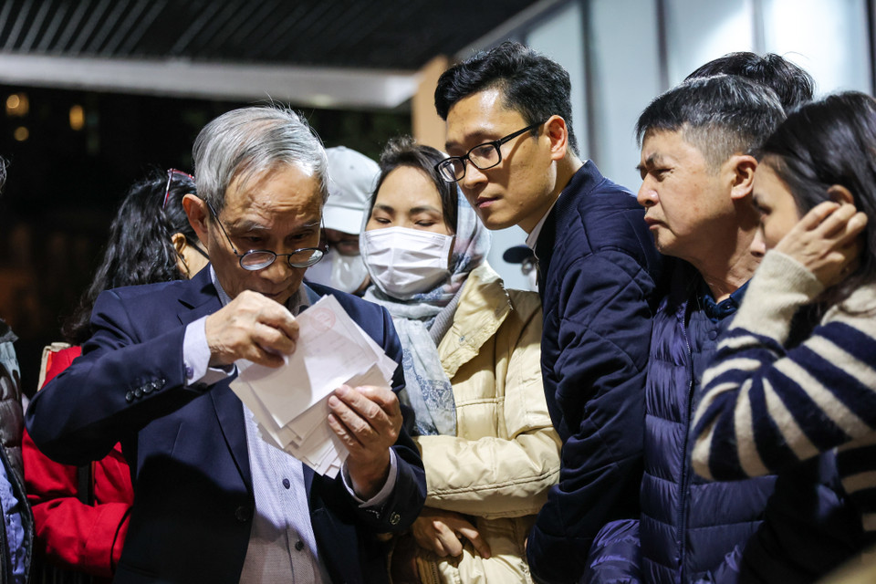 Hiệu trưởng Nguyễn Xuân Khang hỗ trợ các phụ huynh tìm tên con em mình để nộp hồ sơ đăng ký. (Ảnh: Minh Sơn/Vietnam+)