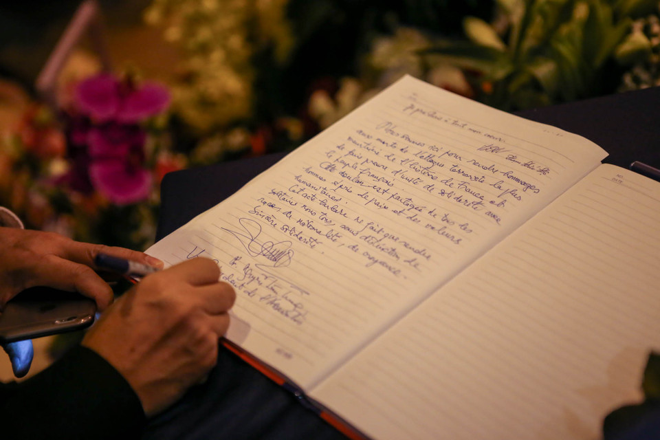 Ông ghi lại những dòng lưu bút thể hiện lòng tiếc thương sâu sắc với những nạn nhân của vụ khủng bố. (Ảnh: Minh Sơn/Vietnam+)