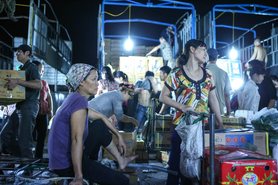 Thế nhưng, nhóm lao động chiếm số đông tại chợ lại là các chị em hành nghề cửu vạn, bốc vác, gánh thuê. Mỗi lần vận chuyển hàng từ xe ra vị trí tập kết, một người được trả từ 20 ngàn đồng. (Ảnh: Minh Sơn/Vietnam+)