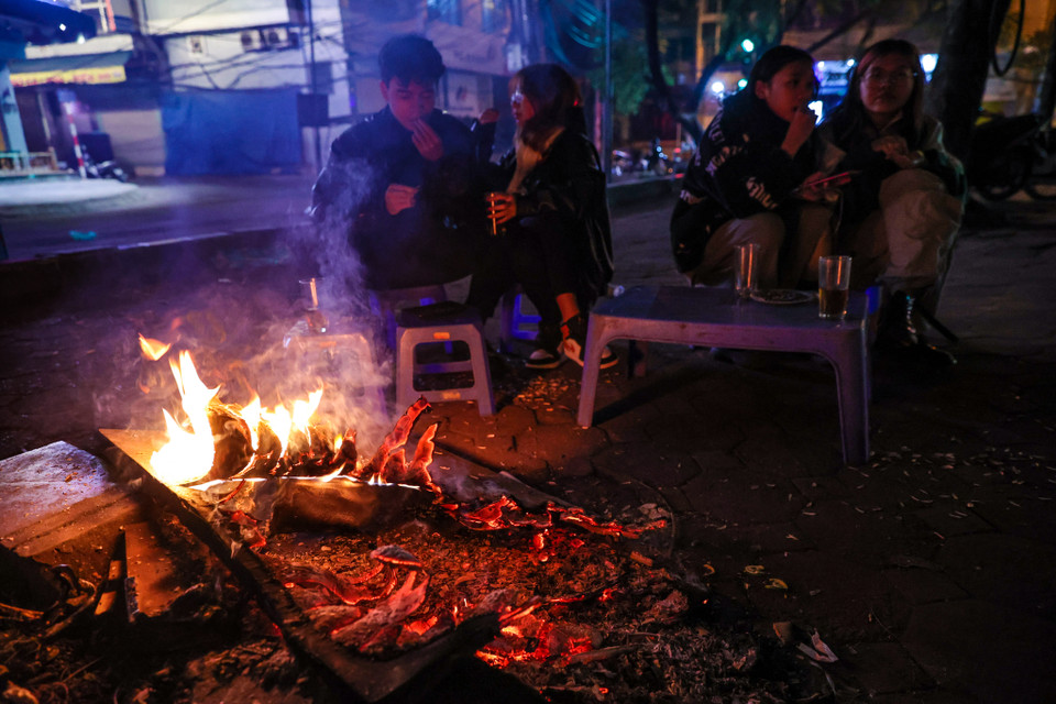 Một quán nước trên đường Hoàng Cầu đã đốt một đống củi khô để phục vụ khách hàng sưởi ấm. (Ảnh: Minh Sơn/Vietnam+)
