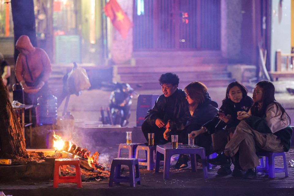 Nhiều quán nước ven đường trở nên bắt mắt hơn khi có những đống lửa bập bùng. Các bạn trẻ tranh thủ dịp này để có thể tụ tập trò chuyện đến đêm trong tiết trời lạnh. (Ảnh: Minh Sơn/Vietnam+)
