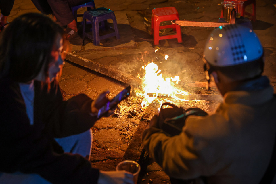 Các khách hàng có thể quây quần quanh đống củi để vừa sưởi ấm vừa tận hưởng không khí lạnh đang tràn về khắp các tuyến phố Hà Nội. (Ảnh: Minh Sơn/Vietnam+)
