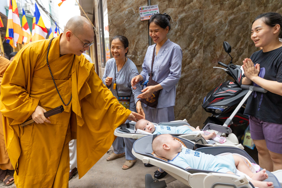 Hai em bé sinh đôi được các sư thầy đi qua chúc phúc. (Ảnh: Minh Sơn/Vietnam+)