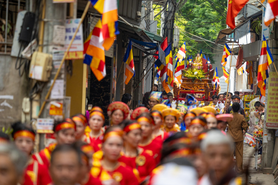 Đoàn người rước Đức Phật, hoa, cờ diễu hành qua các con ngõ nhỏ ở làng Bằng Liệt. (Ảnh: Minh Sơn/Vietnam+)