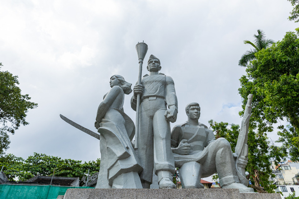 Được cố nghệ sĩ Kim Giao sáng tác năm 1984, công trình thể hiện hình ảnh ba nhân vật: Ở giữa là người chiến sĩ Vệ quốc đoàn cầm bom ba càng, hai bên là cô gái mặc áo dài cầm gươm và anh công nhân ngồi cầm súng.