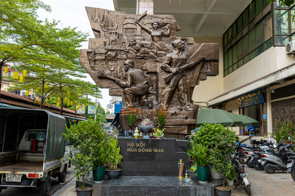 Mặt trước của tấm phù điêu có hình ảnh các chiến sĩ cảm tử quân ôm bom ba càng, đây là một hình ảnh mang tính biểu tượng cho sự kiện 60 ngày đêm bảo vệ Thủ đô. Cùng với đó có hình ảnh anh bộ đội cầm súng, công nhân, phụ nữ Thủ đô cùng sát cánh bên các chiến sĩ bảo vệ Hà Nội. Trên nền là những mái nhà của phố cổ lô xô, dáng hình chợ Đồng Xuân và ô Quan Chưởng xưa.