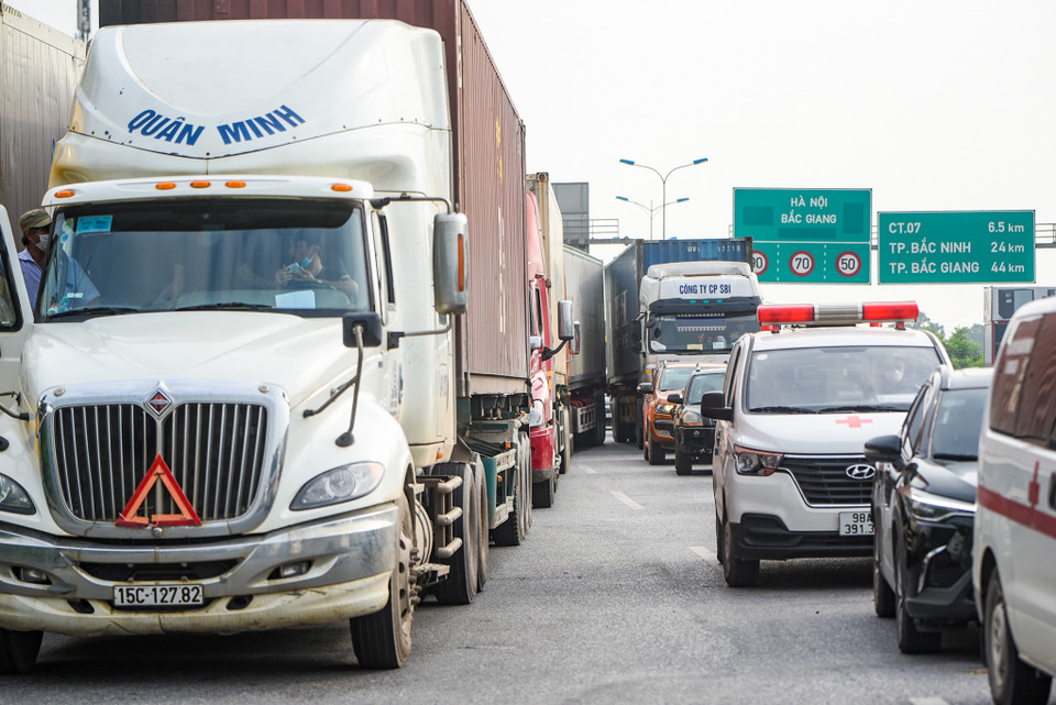 Nguyên nhân được Tổng cục Đường bộ xác định là do các phương tiện chủ yếu là lái xe container, xe tải lớn có biển kiểm soát của các tỉnh phía Nam di chuyển dài ngày lên phía Bắc khi quay về đến địa giới Hà Nội thì Thành phố áp dụng Chỉ thị 16 nên không kịp chuẩn bị các điều kiện để cấp phép thẻ 'luồng xanh' hoặc chưa chuẩn bị kịp các giấy tờ theo quy định của Hà Nội. (Ảnh: Minh Sơn/Vietnam+)
