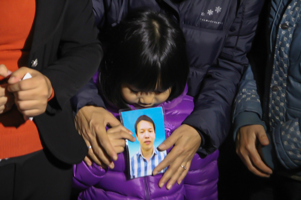 Cầm trên tay di ảnh của người cha xấu số, bé Diệp vẫn còn quá nhỏ để biết rằng, người cha thân yêu đã ra đi mãi mãi. (Ảnh Minh Sơn/Vietnam+)