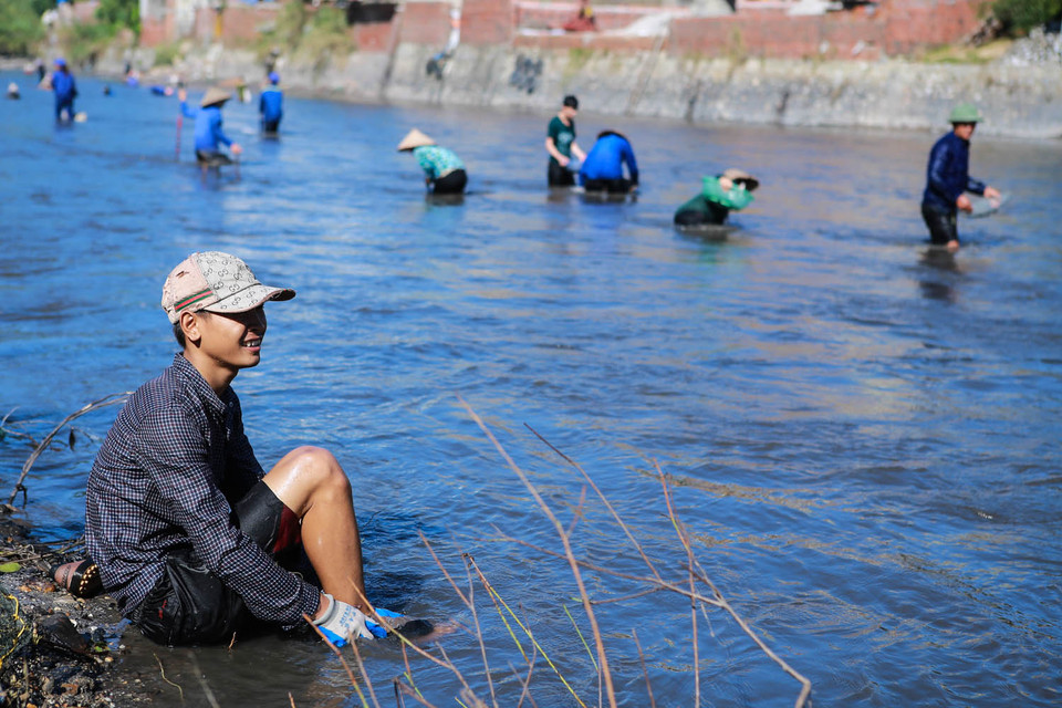 Chàng thanh niên này bị một mảnh đá dăm cứa vào chân nên phải lên bờ tạm nghỉ​. ​Anh cho biết một ngày chăm chi anh có thể vớt được hơn 1 tấn than đủ loại. (Ảnh: Minh Sơn/Vietnam+)