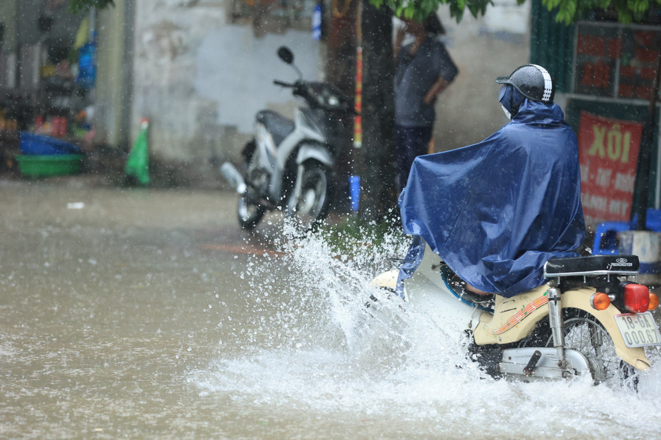 Cơn mưa lớn bất chợt khiến nhiều người dân Thủ đô đi làm chật vật vì đường ngập sâu. (Ảnh: Hoài Nam/Vietnam+)