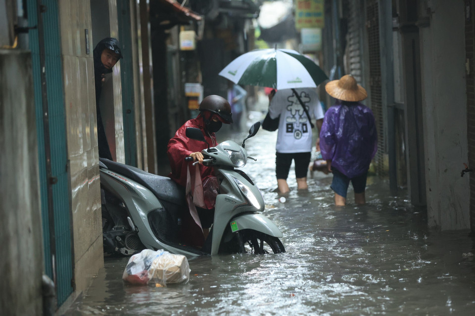 Trong khu vực đường Triều Khúc, nhiều gia đình vật lộn với cảnh thoát khỏi khu vực ngập để đi làm. (Ảnh: Hoài Nam/Vietnam+)