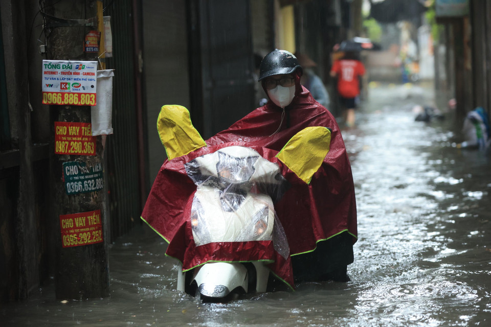 Người dân phải dắt xe qua chỗ nước ngập sâu vì chết máy. (Ảnh: Hoài Nam/Vietnam+)