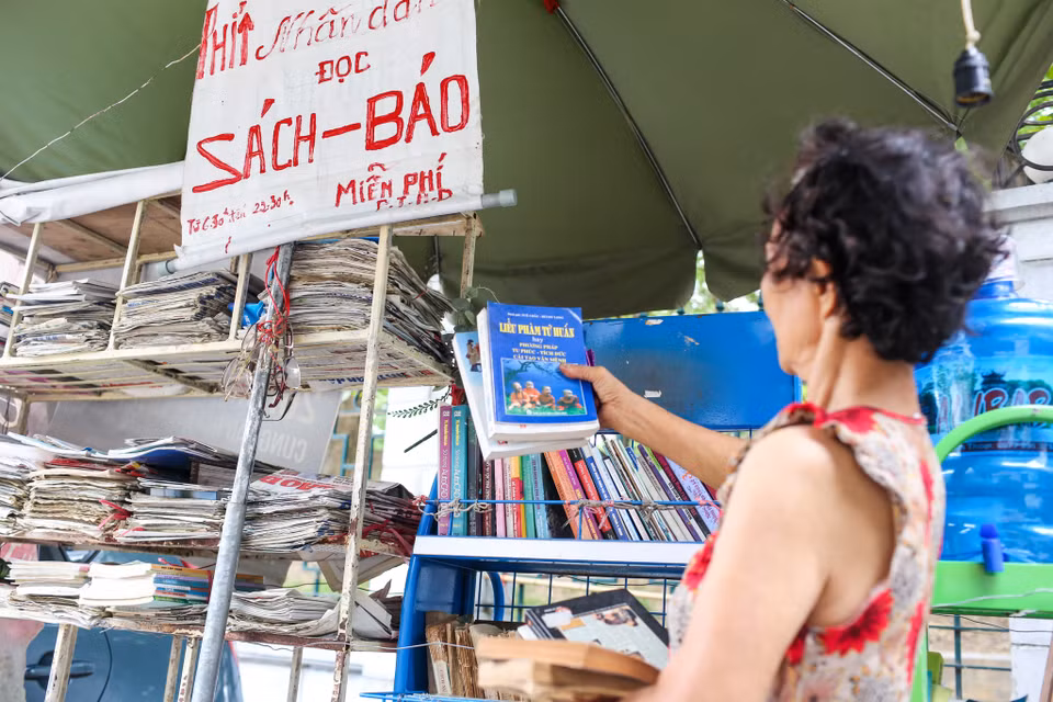 Kệ báo của bà mở cửa hàng ngày từ 6 giờ 30 sáng đến tận 22 giờ đêm. Không chỉ người cao tuổi, nhiều bạn trẻ cũng thích thú với quầy báo này. (Ảnh: Minh Sơn/Vietnam)