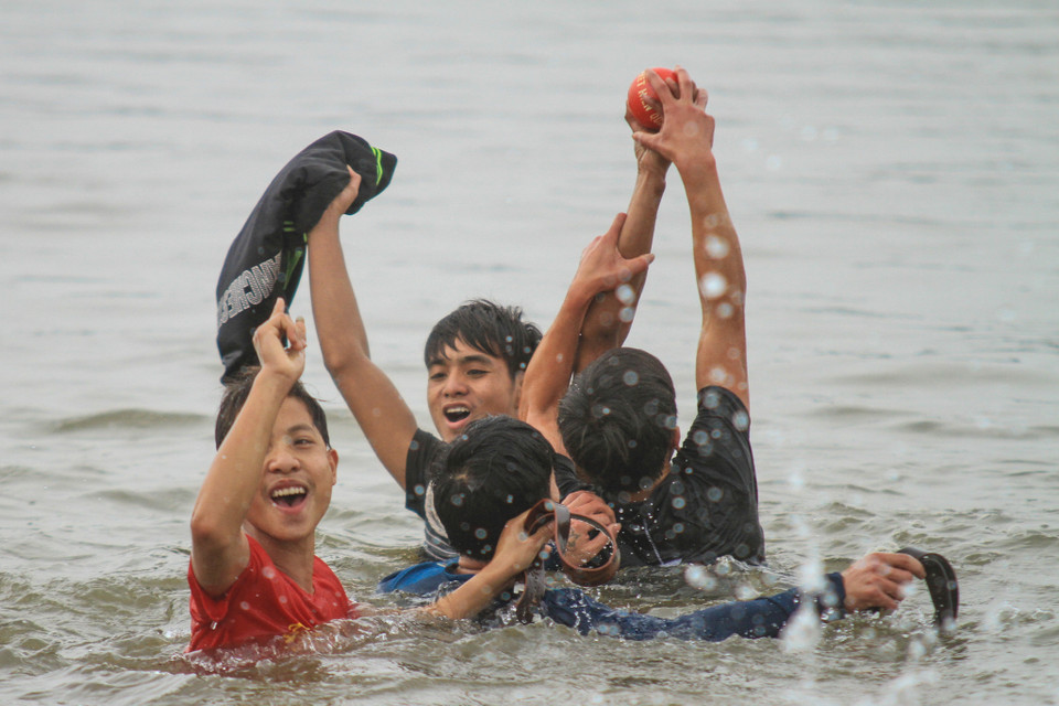 Một nhóm thanh niên giành được quả phết đầu tiên đã bơi ra giữa sông để ngăn không cho nhóm khác cướp lại. (Ảnh: Minh Sơn/Vietnam+)