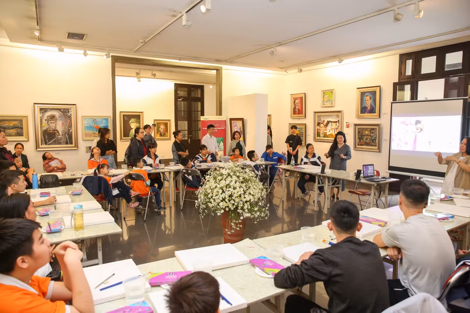 Nữ hoạ sỹ Văn Dương Thành và bốn bạn Nguyễn Quang Minh, Nguyễn Linh Chi, Trần Khánh Linh và Lê Châu Anh cùng hướng dẫn các bạn nhỏ đến từ trường Phổ thông Cơ sở Dân lập Dạy trẻ câm điếc Hà Nội tập vẽ những bức tranh đầy sinh động. (Ảnh: Minh Sơn/Vietnam+)